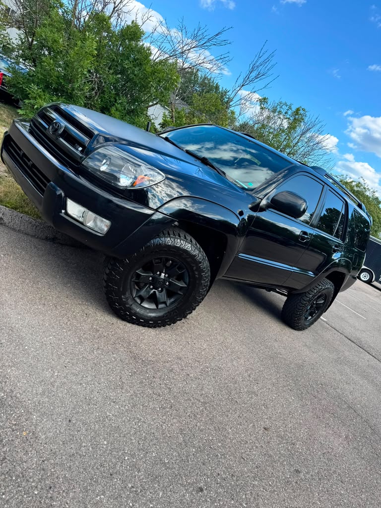 Black Toyota 4Runner with black aftermarket wheels and all-terrain tires.