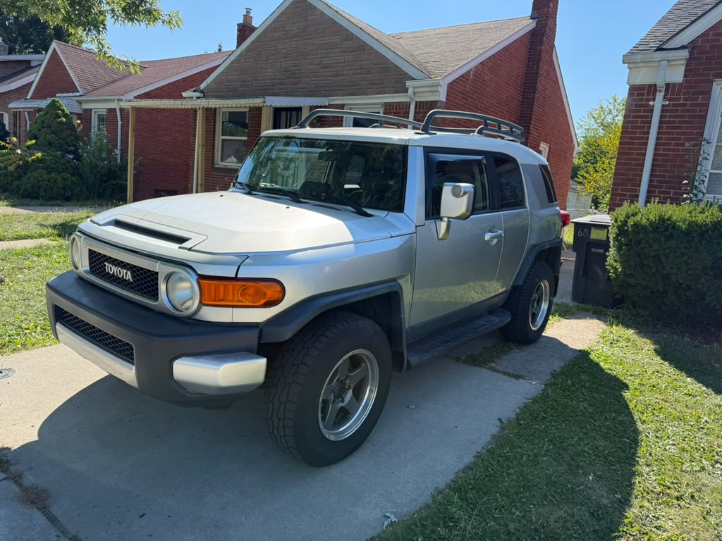 Silver Toyota FJ Cruiser with chrome wheels parked in a driveway.